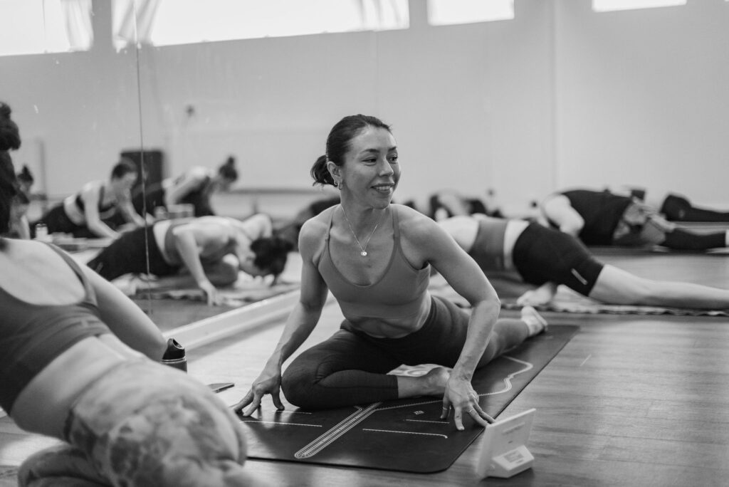 Leende deltagare i höftöppnare under en hot yoga-klass