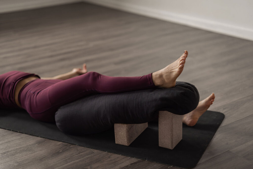 Yin yoga-position med bolster och block under benen