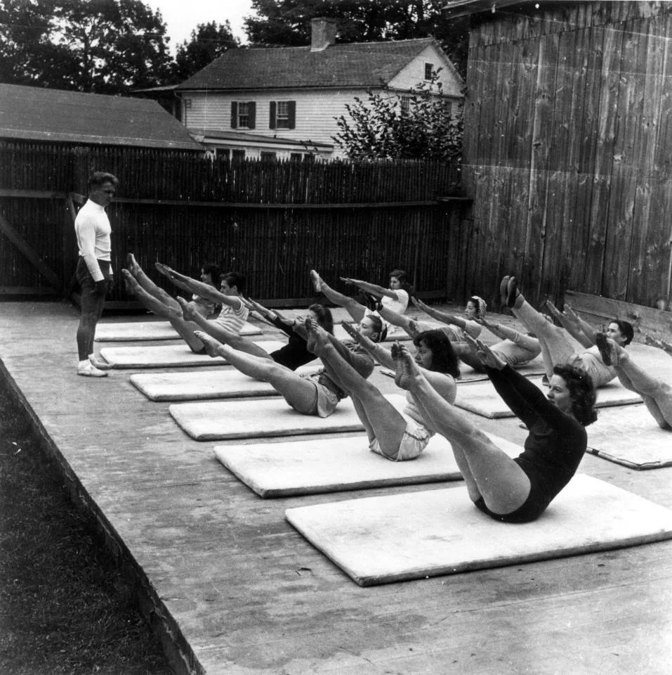 Joseph Pilates leder en mattklass med dansare utomhus på Jacob's Pillow i Massachusetts
